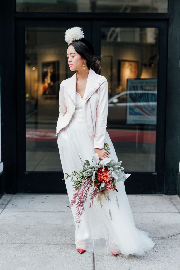 Chanel in downtown San Francisco wearing ethically-made Celia Grace wedding dress, Brevity Brand jacket, Soko jewelry, and vintage accessories showcasing Claire Xue florals
