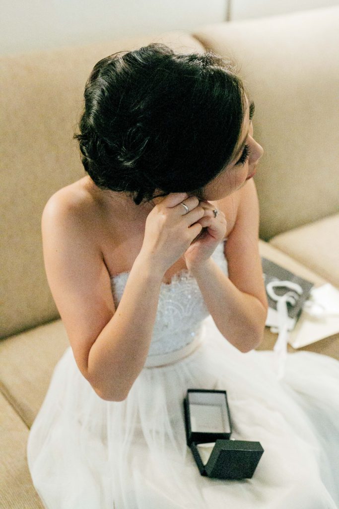 bride puts in earring on wedding day