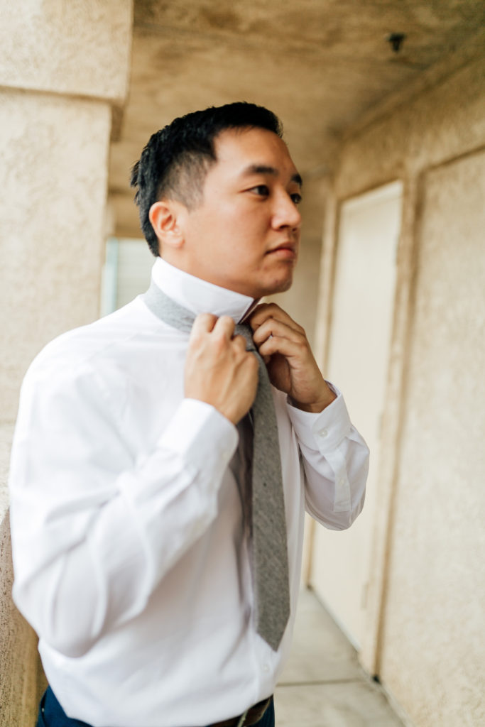 groom finishes putting on his tie