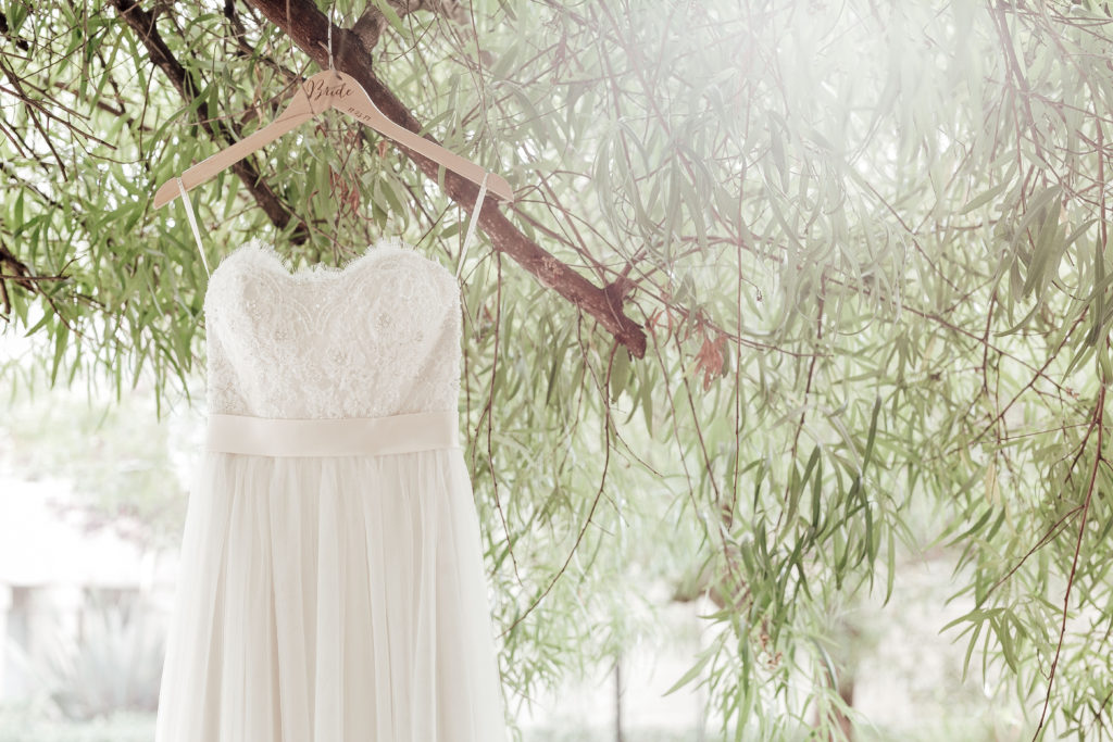 wedding dress hangs from branch of tree