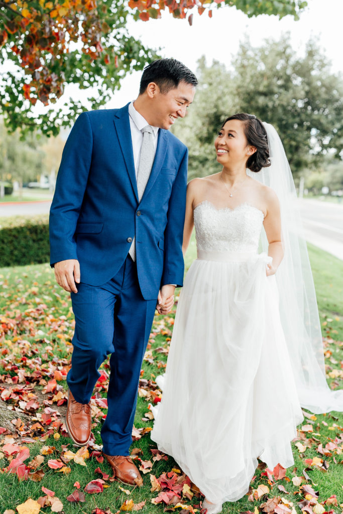 bride and groom walk together through fall scenery