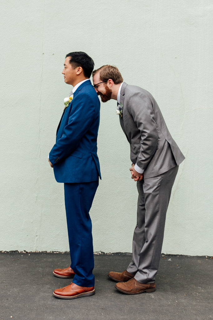 groom and one of his friends stand sideways and silly
