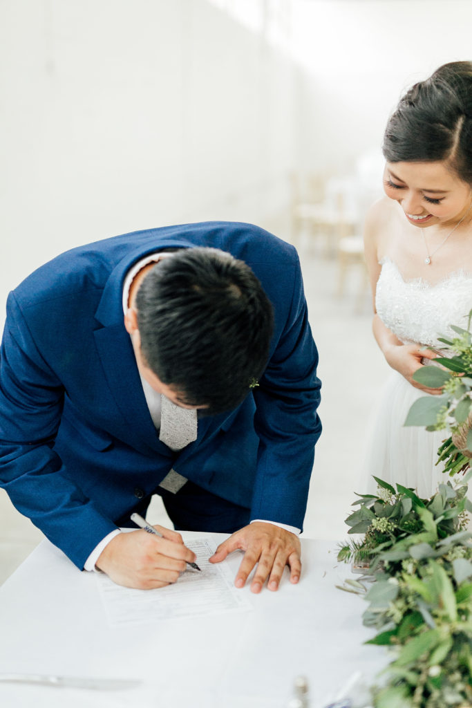 Groom signs document at ceremony