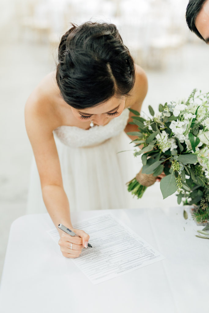 Bride signs document at ceremony