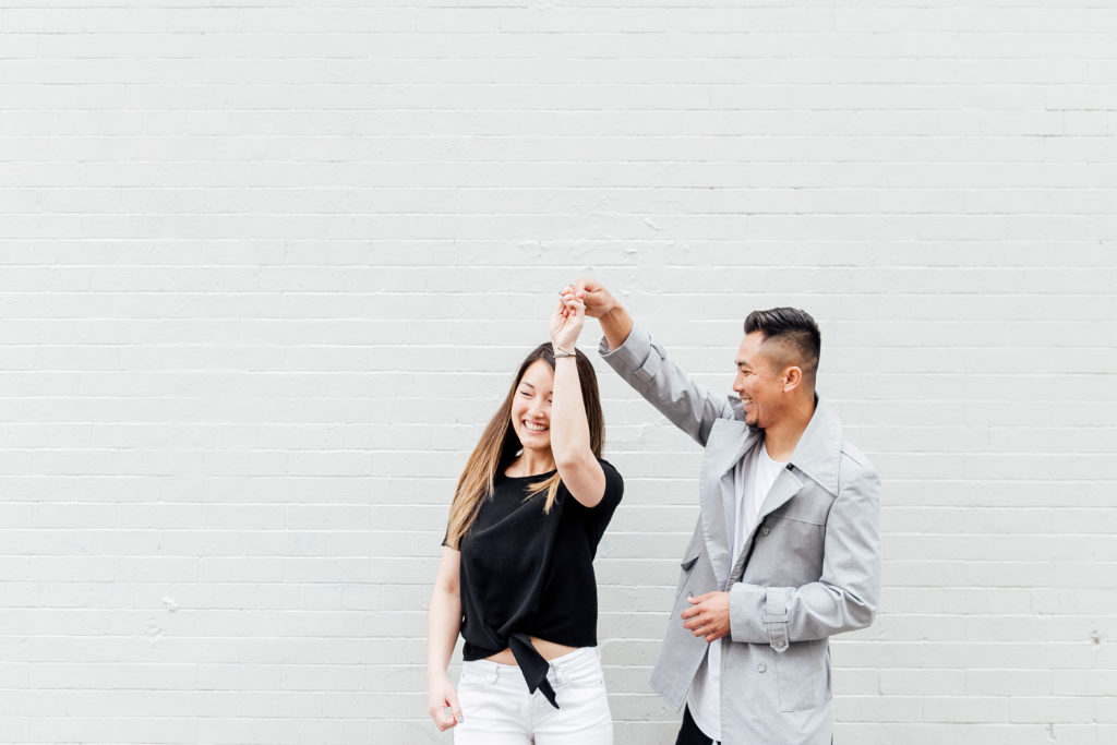 couple dances together in front of a white wall 