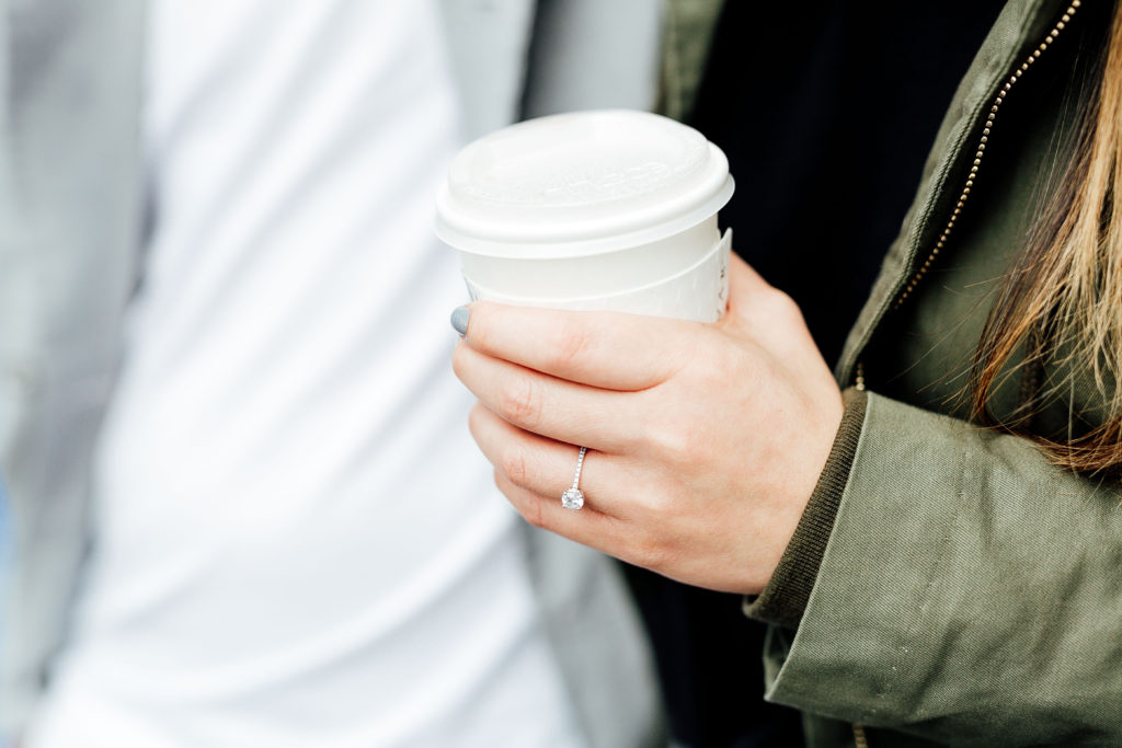 close-up shot of fiancée's hand, holding coffee cup and with engagement ring showing