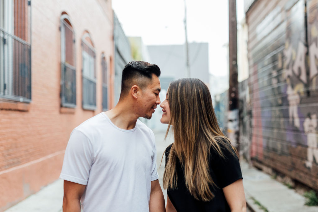 profile photo of couple as they touch noses while standing in an alley