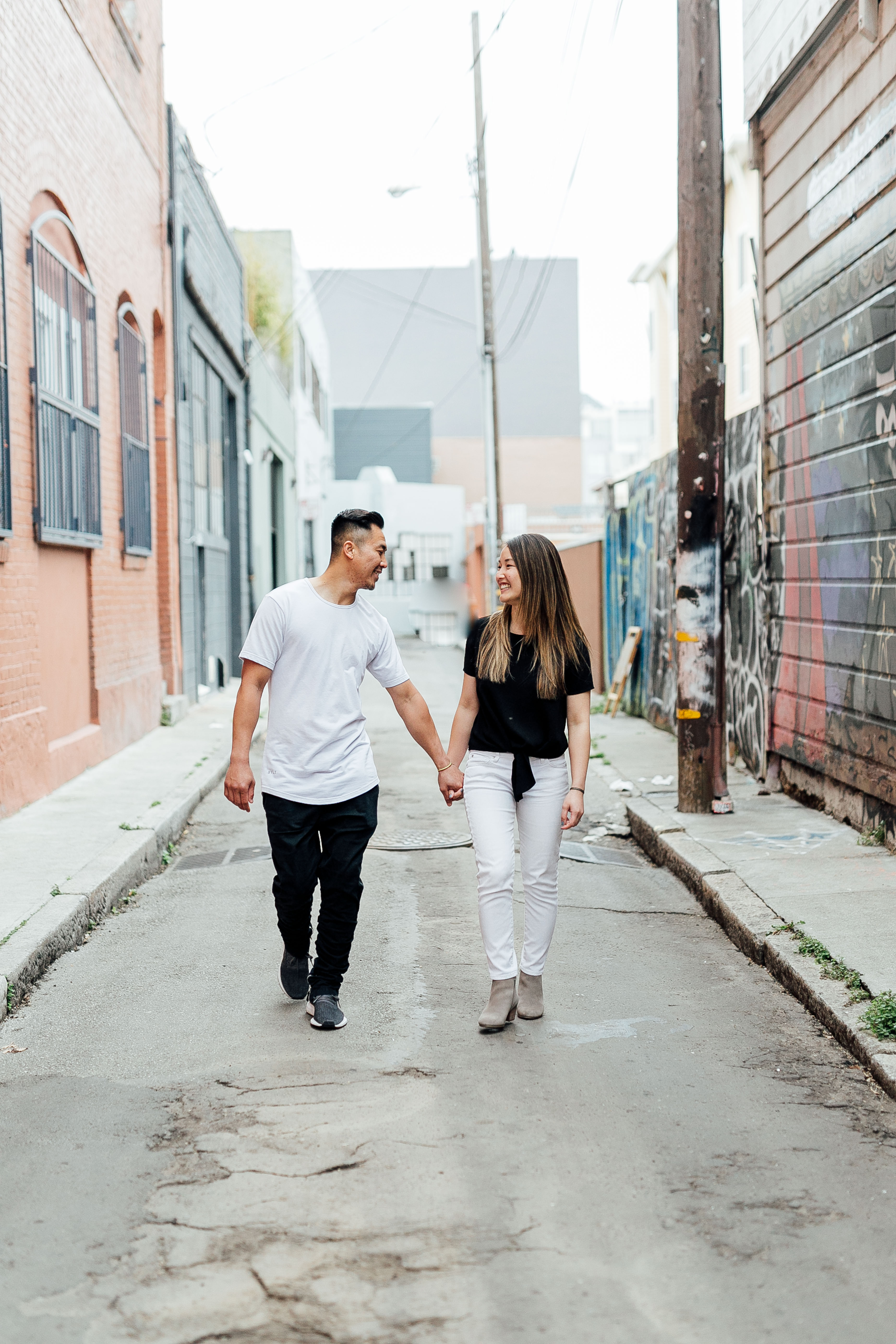 couple strolls through the colorful alley, looking at each other