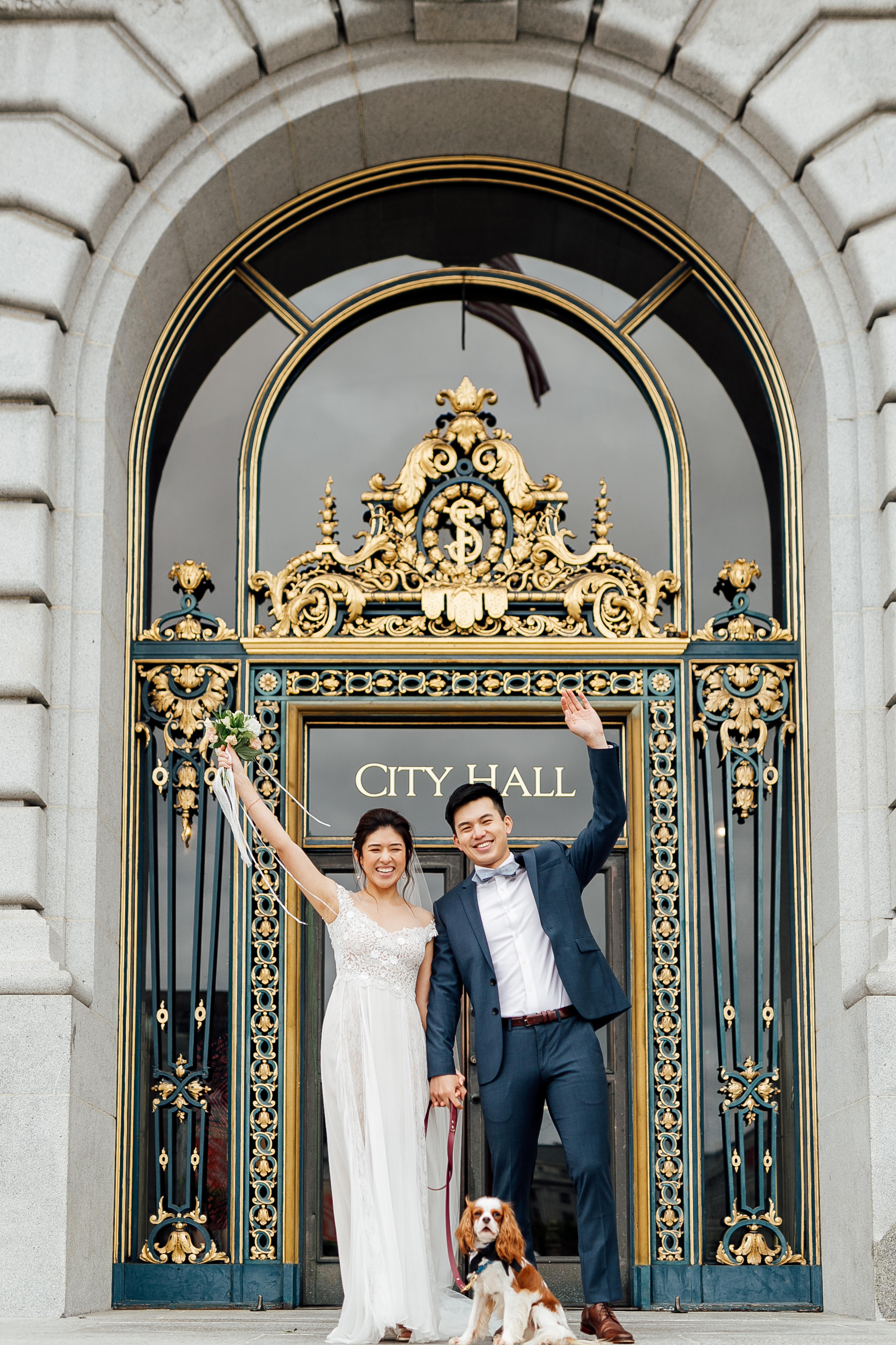 Bride, groom, and dog rejoice in front of City Hall doors