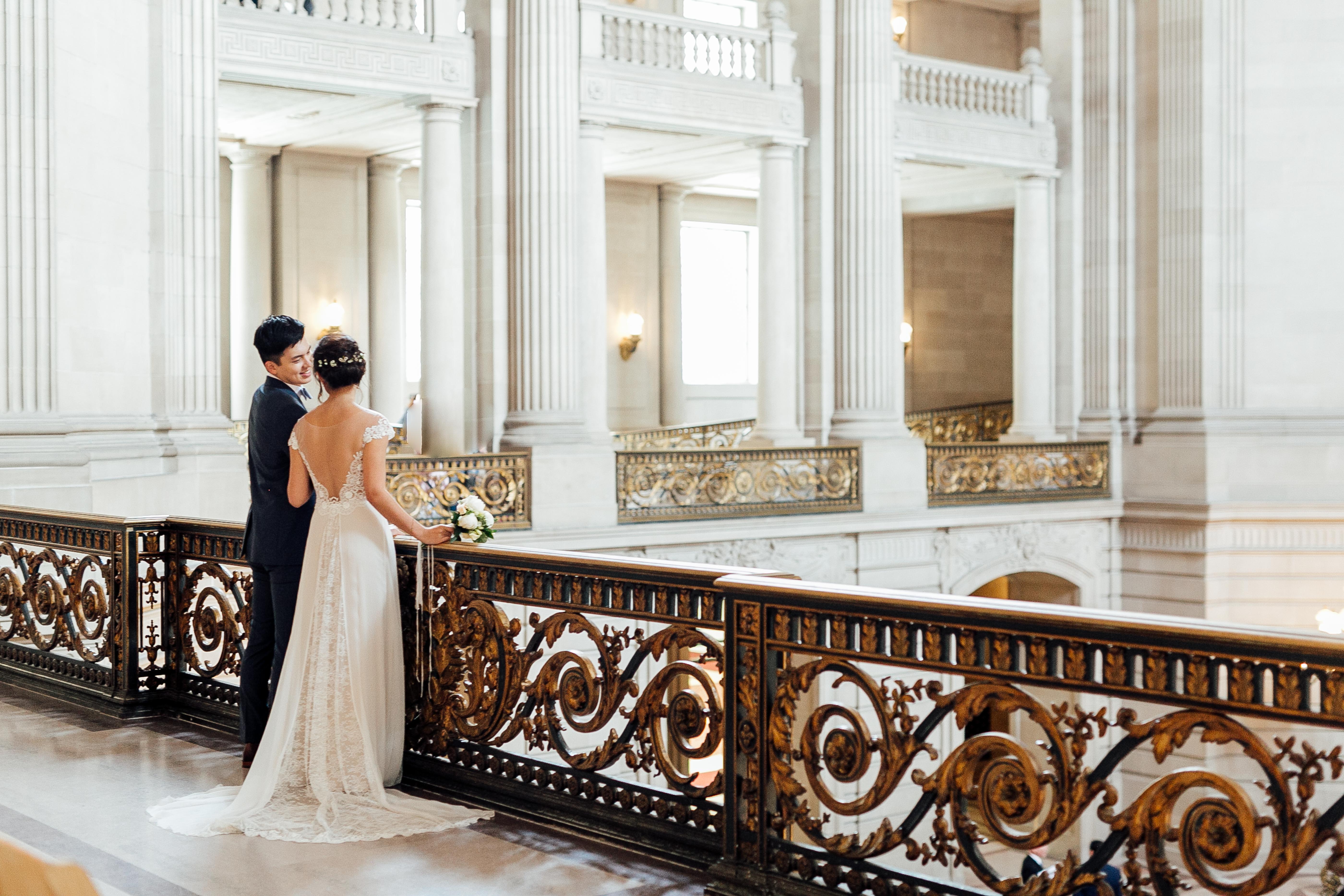 Bride and groom stand on elegant balcony of City Hall