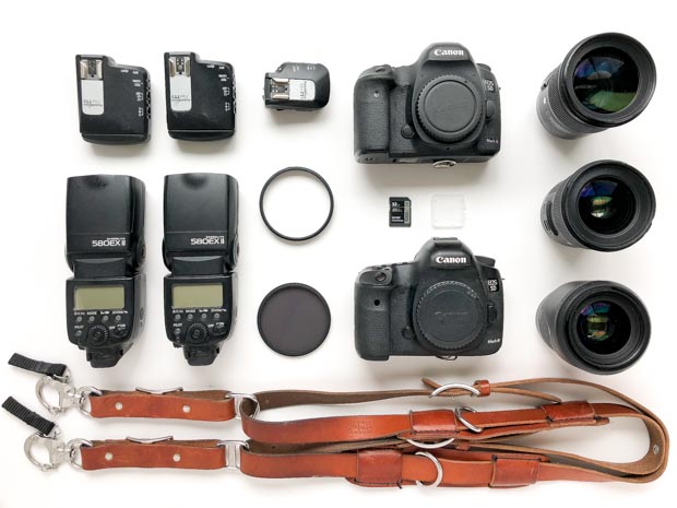 Flat lay of photo gear: Canon 5dM3, Sigma 24mm, Sigma 50mm, Sigma 35mm lenses, Holdfast straps, 580EXii's