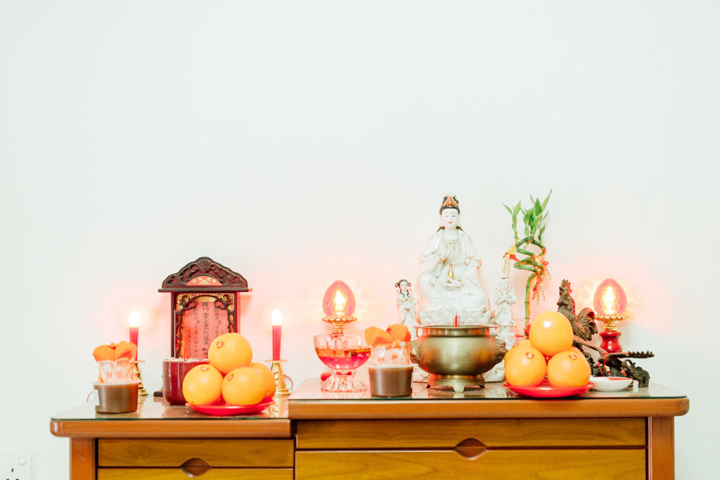 Offerings and sacred objects on dresser, against white wall