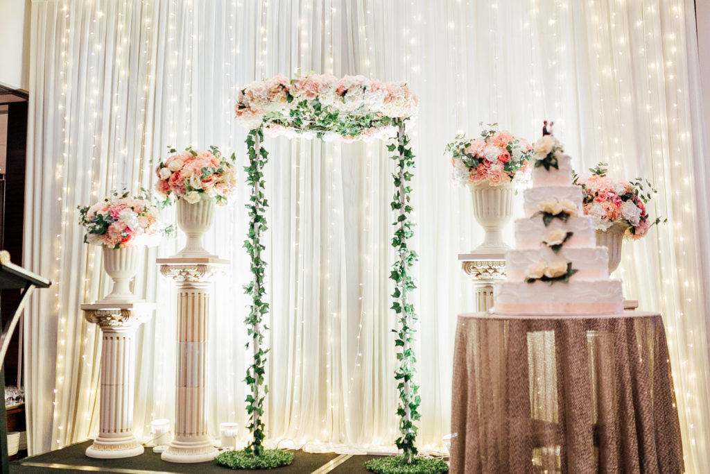Flowers, cake, and lights against white backdrop