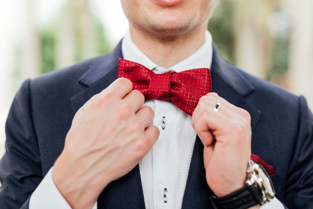 Detail shot of groom fixing his bow tie