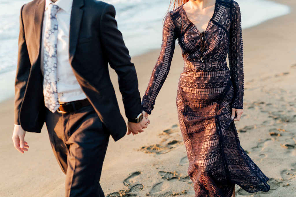 Couple holds hand, walks on beach