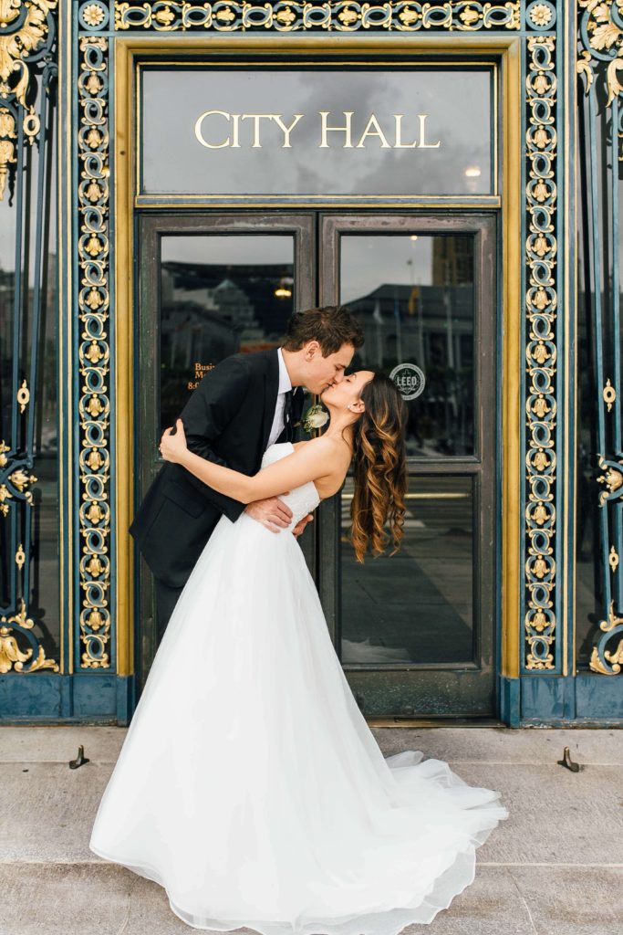 A bride and groom kiss in front of City Hall in San Francisco for one of the most beautiful city hall wedding photos.