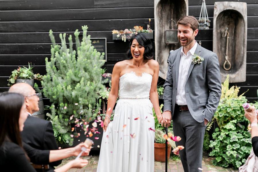 The bride and groom greet their guests for the first time as a married couple, and guests blast floral confetti at them, a unique ethical wedding idea!