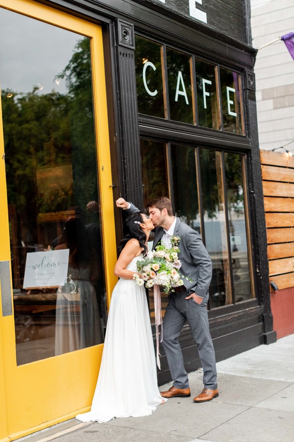 the bride and groom kiss in front the stable cafe before their ethical wedding in San Francisco.