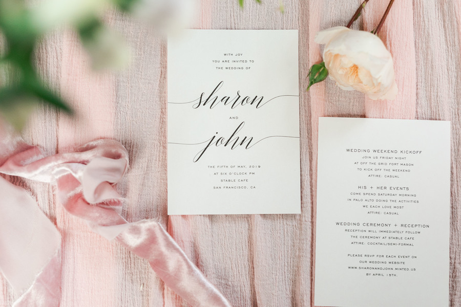 A flatlay photo of John and Sharon's green wedding invitations to their San Francisco ethical wedding.