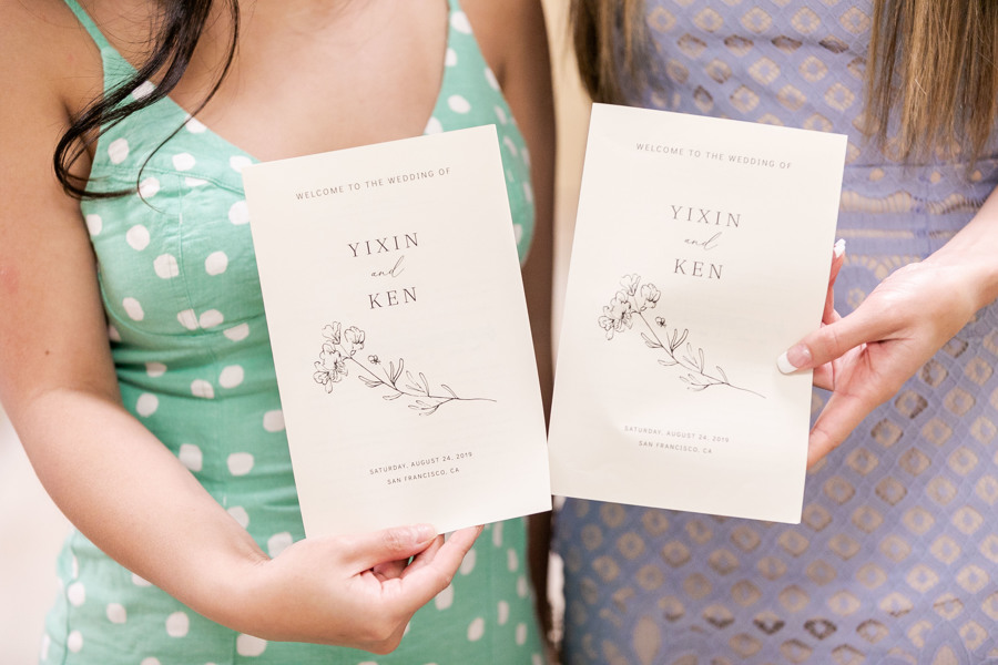 Two wedding guests hold invitations to a wedding in San Francisco, CA.