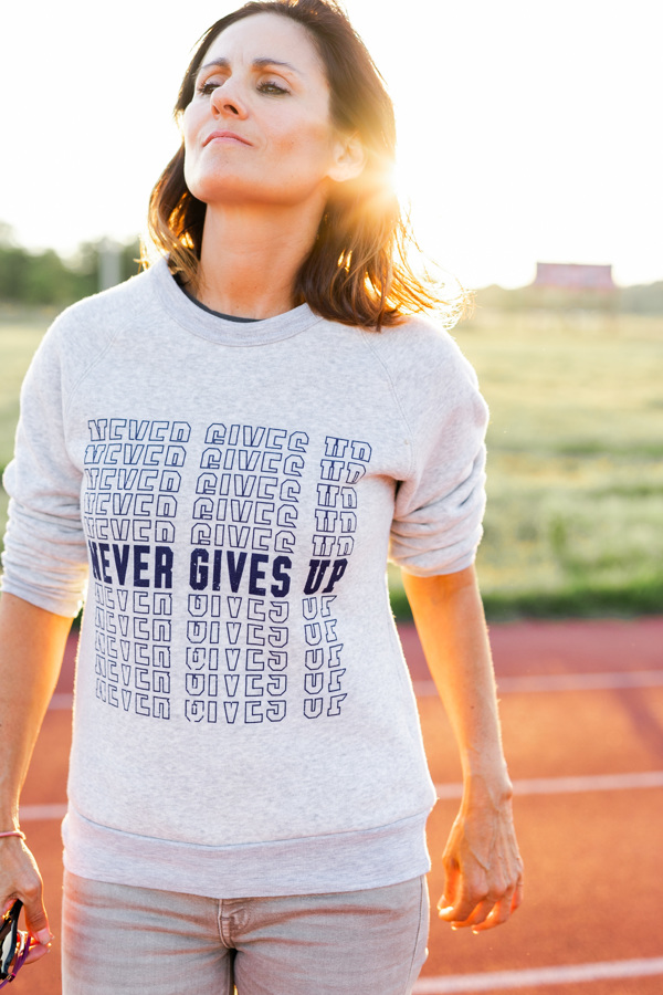 Never Gives Up is the career motto that helps when making career pivots like Janel Broderick did, featured here wearing a custom design sweatshirt from her t-shirt brand.
