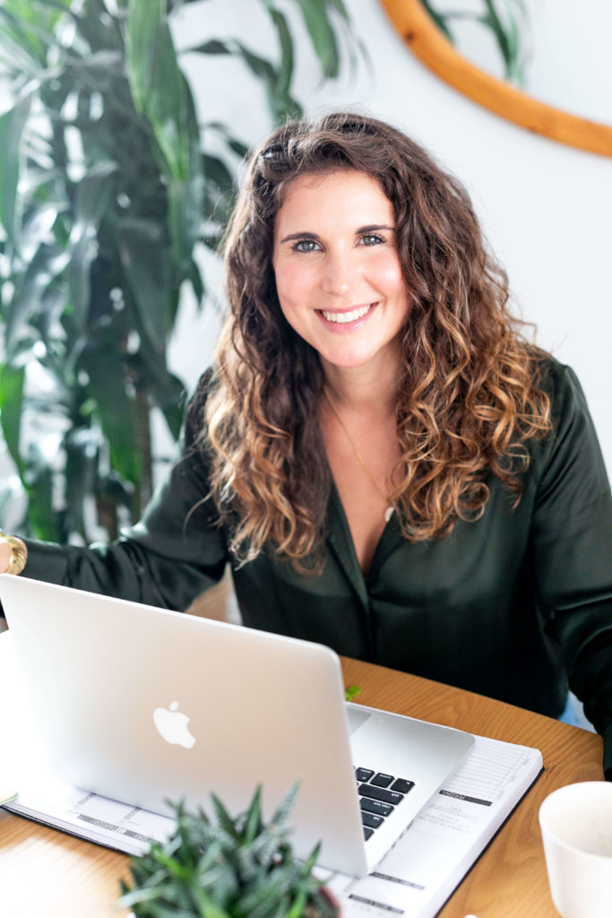 A branding headshot of life coach, Stefani McCullah, who works from her laptop.