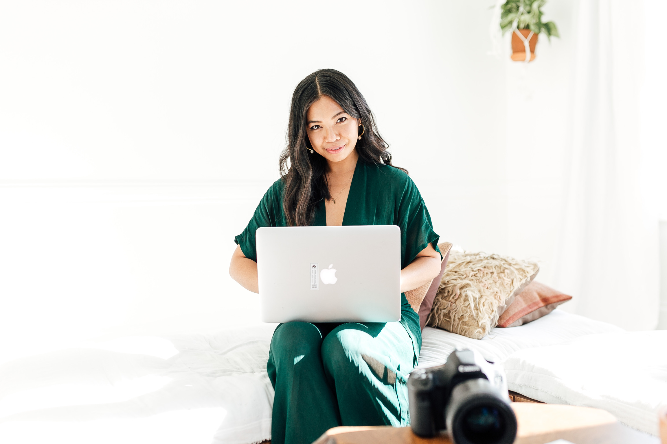 Woman in green dress typing on a computer with camera in foreground